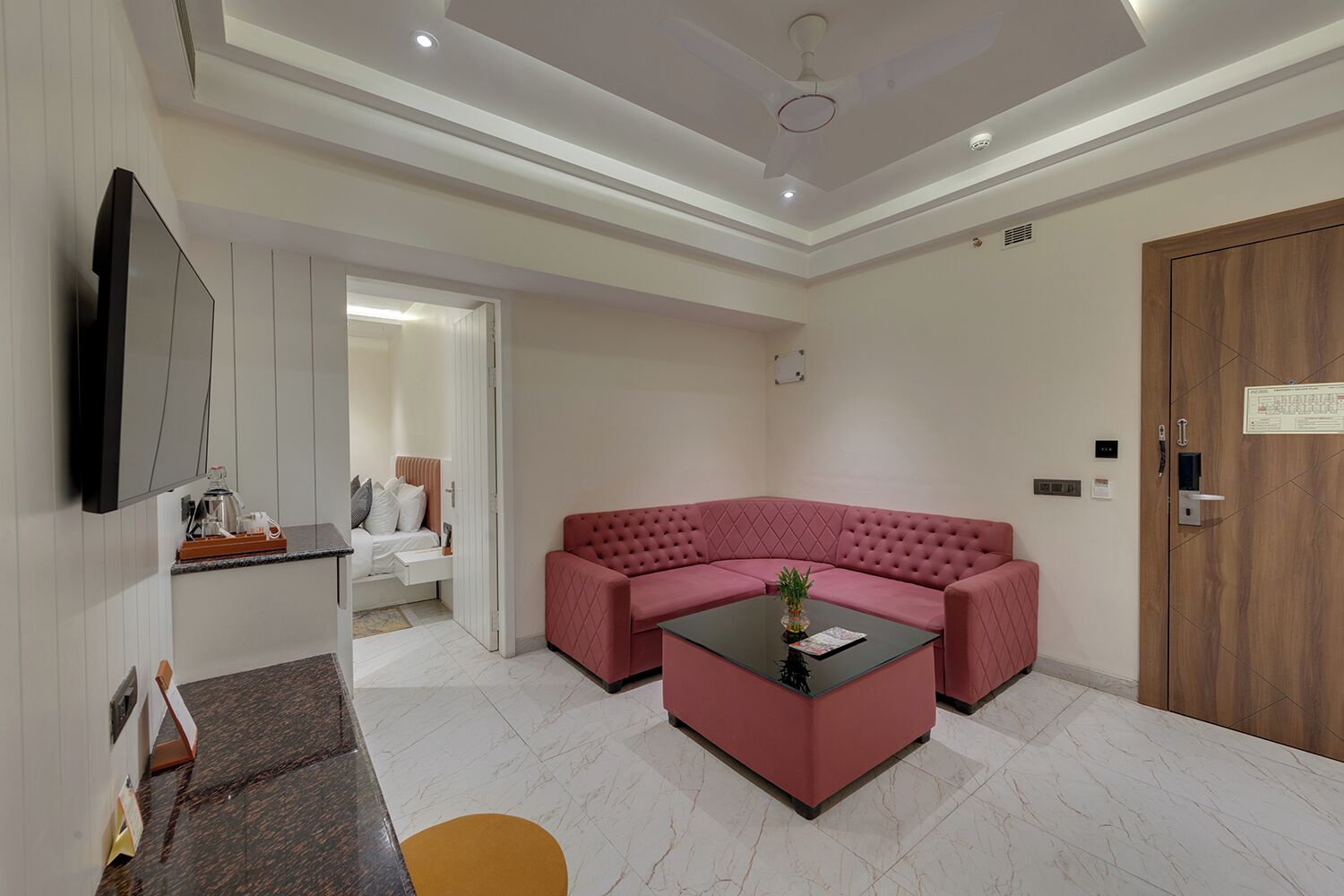 A modern living room with a sectional sofa, a coffee table, a flat-screen TV, and a wooden door.