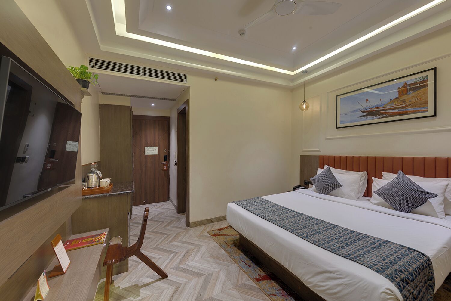 Habitación de hotel con una cama grande, un televisor de pantalla plana, un cuadro en la pared y una puerta de madera.