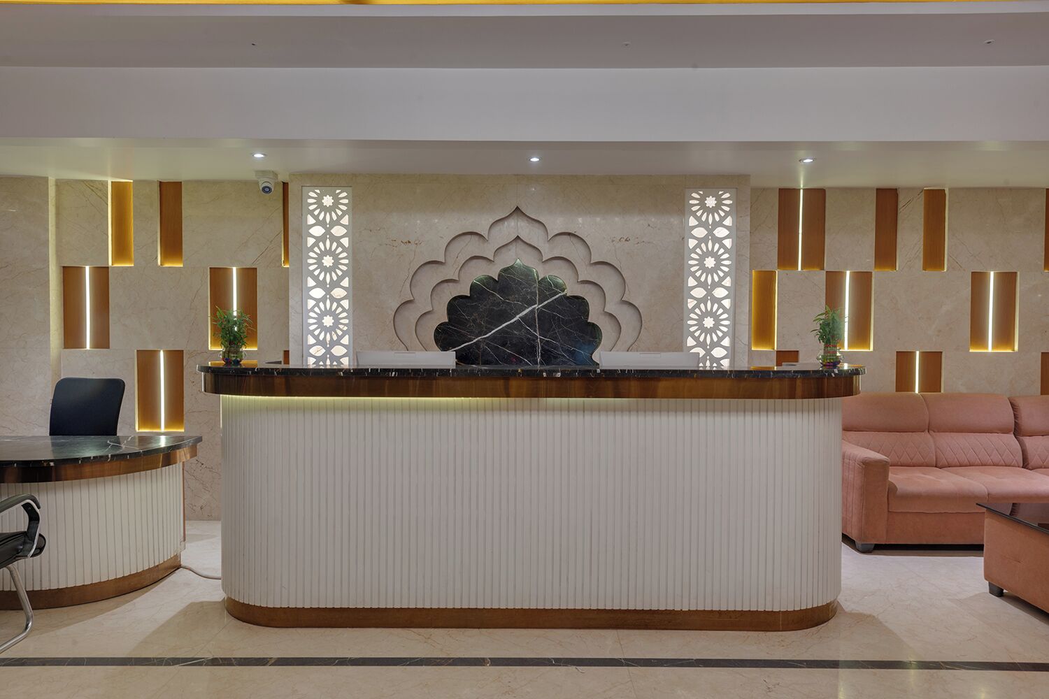 A reception desk with a modern design, a large decorative leaf motif, and a sofa in the background.