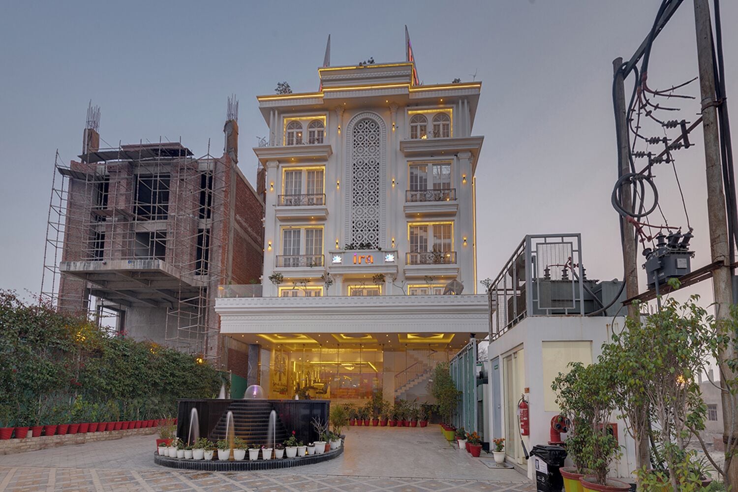 A multi-story hotel with a grand entrance, a fountain in the courtyard, and a well-maintained garden.