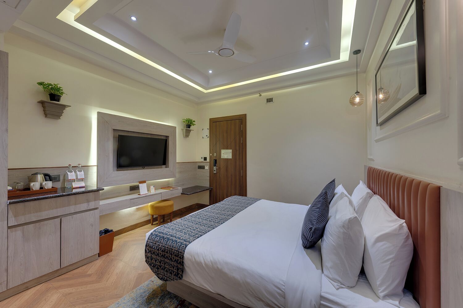 A modern hotel room with a bed, a TV, a desk, and a bathroom.
