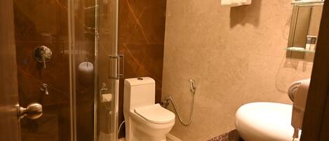 A modern bathroom with a glass-enclosed shower, a toilet, and a sink with a marble countertop.