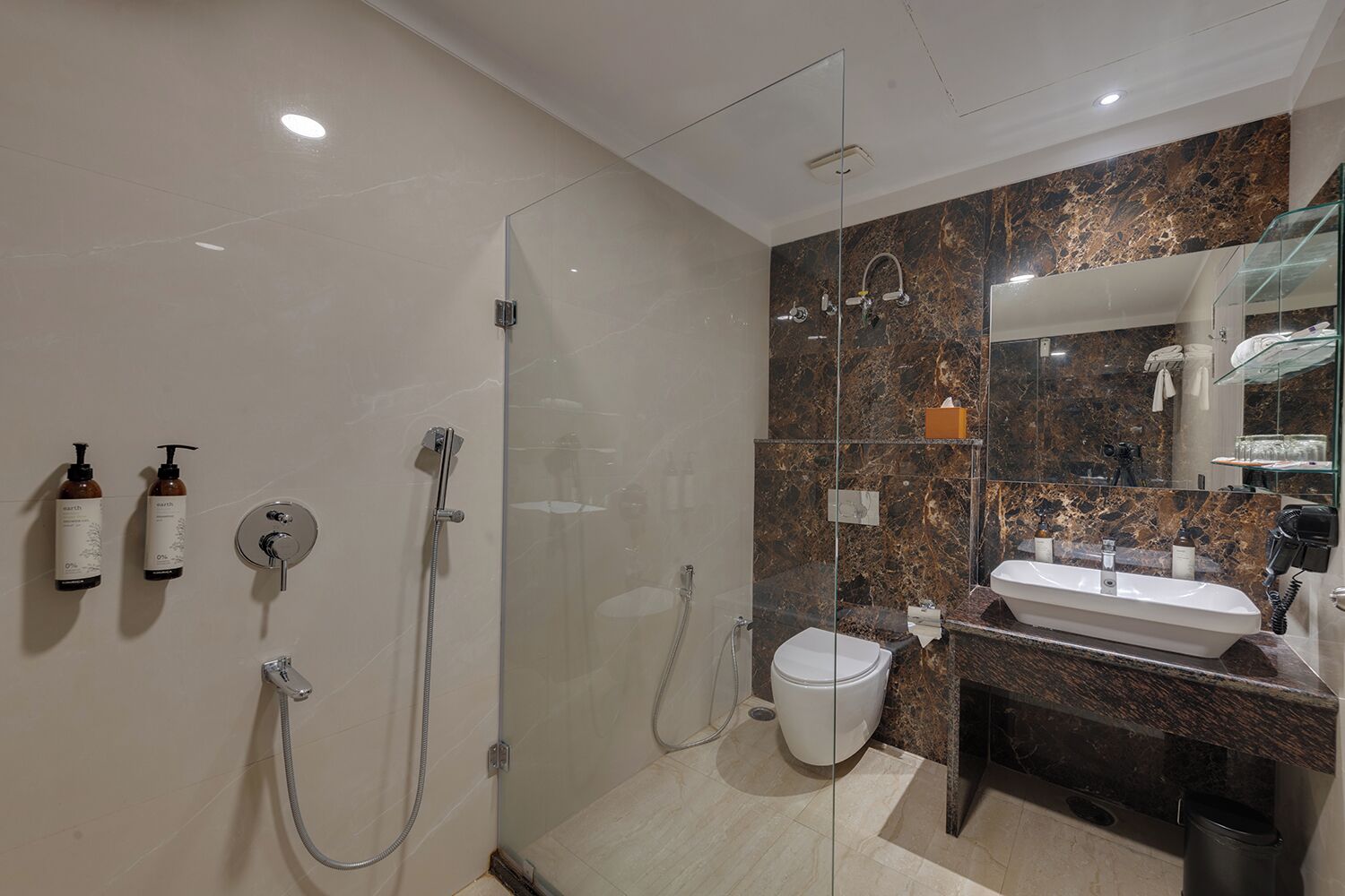 A modern bathroom with a glass-enclosed shower, a white toilet, and a vanity with a marble countertop.