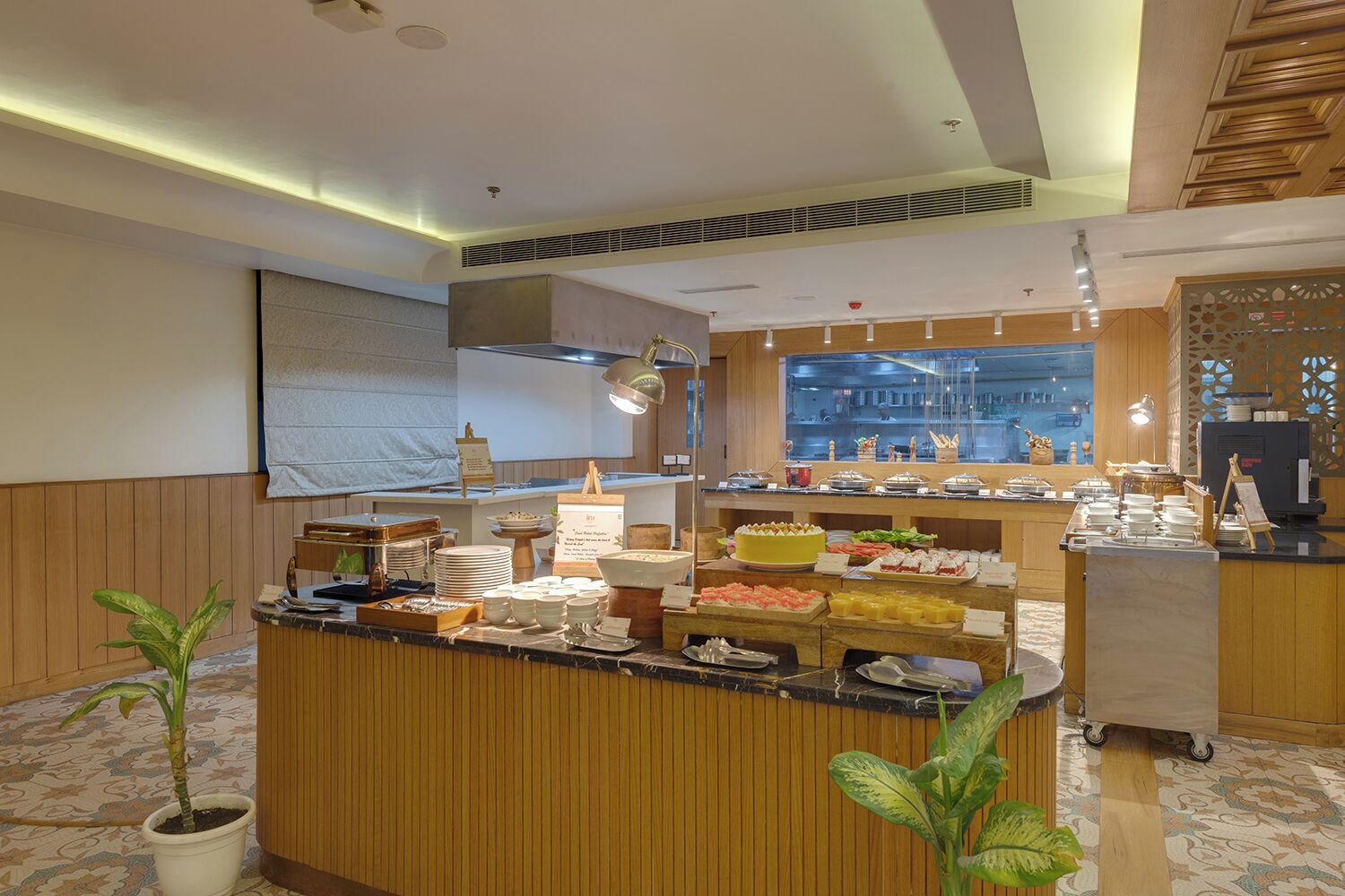A buffet setup with various food items, a wooden counter, and a view of the kitchen in the background.