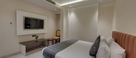 Una habitación de hotel moderna con cama, televisor, escritorio y silla.