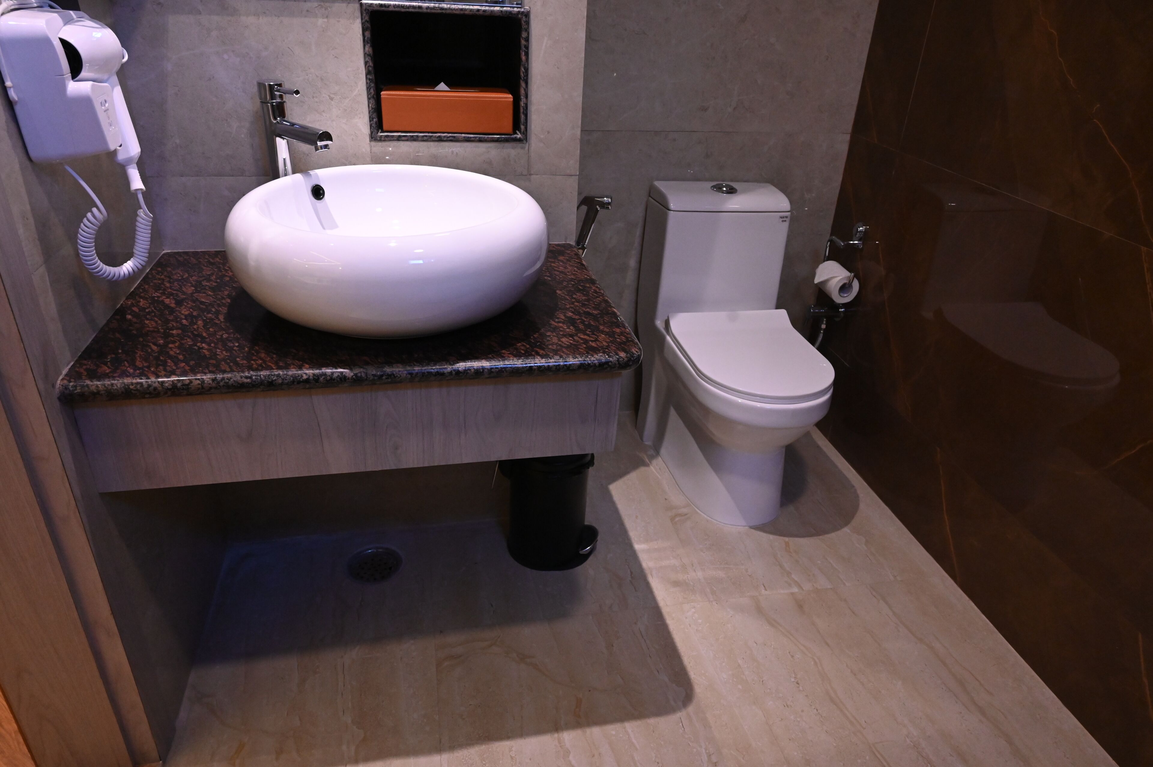 Ein Badezimmer mit Waschbecken, Toilette und einem Föhn an der Wand.