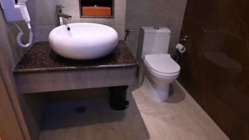 Een badkamer met een wit wastafel, toilet en een haardroger aan de muur.