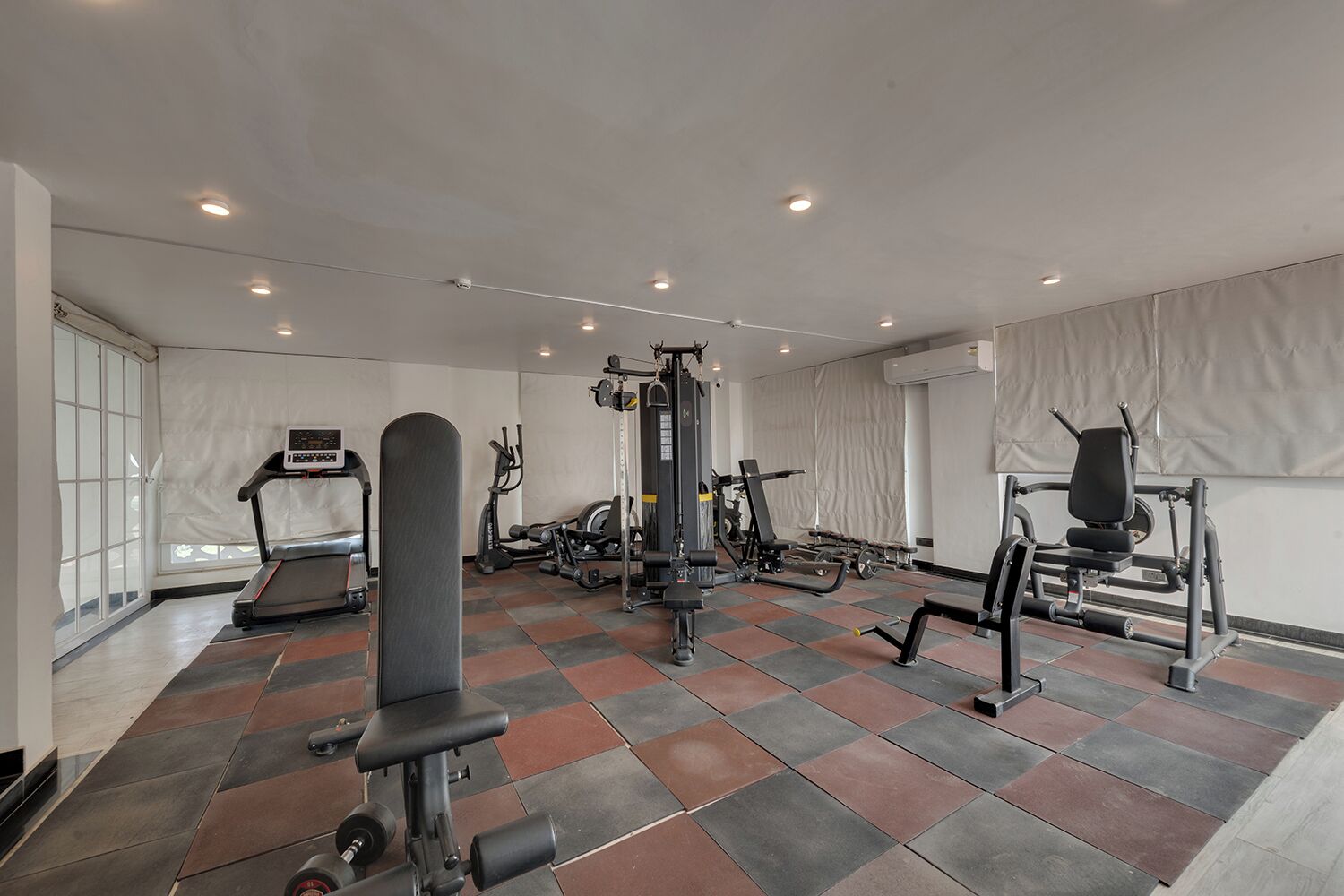 A gym with various exercise equipment, a treadmill, and a weight bench.