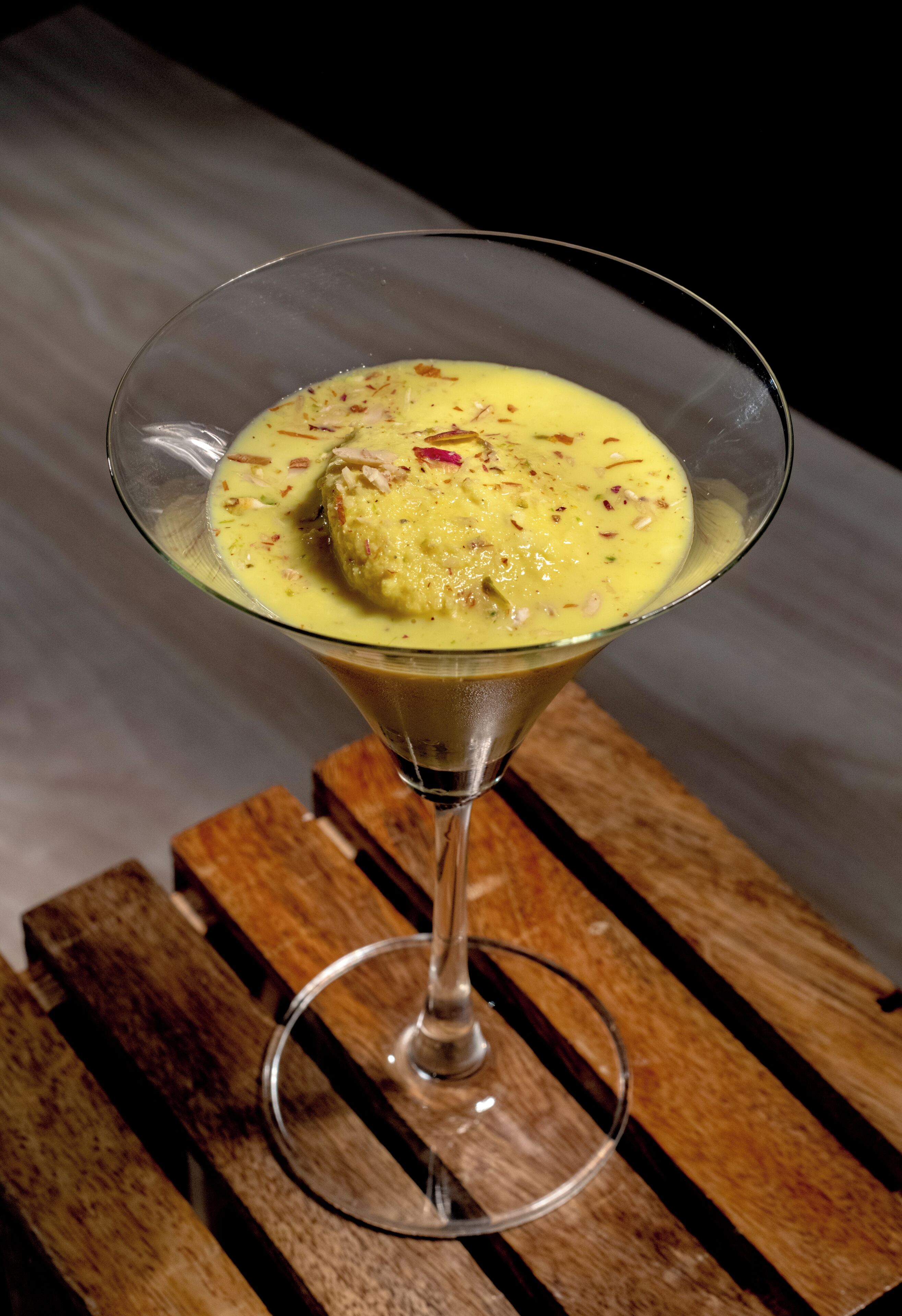 A dessert in a martini glass on a wooden surface.