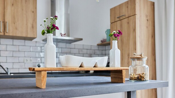 A kitchen counter with a wooden tray holding a white bowl and two white vases with flowers. - Beautiful apartment in Attendorn (Attendorn)