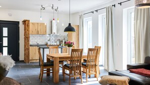 A modern kitchen with wooden cabinets, a dining table with chairs, and pendant lighting. - Beautiful apartment in Attendorn (Attendorn)