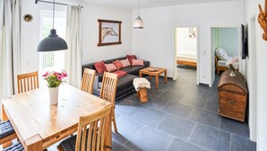 A modern living room with a sofa, dining table, chairs, and a small wooden cabinet. - Beautiful apartment in Attendorn (Attendorn)