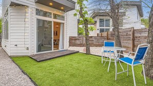 Uma casa moderna com um pátio, porta de correr de vidro e um espaço de estar ao ar livre com mesa e cadeiras.