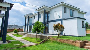 A modern two-story building with a flat roof, large windows, and a concrete pathway leading to the entrance. - DivineHeights Apartment Lilongwe Area 43 (Lilongwe)