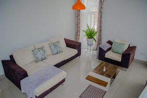 Una sala de estar moderna con un sofá, un sillón, una mesa de centro y una planta en maceta.