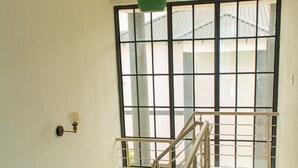 A staircase with metal railings and a view of a building outside through large windows. - DivineHeights Apartment Lilongwe Area 43 (Lilongwe)