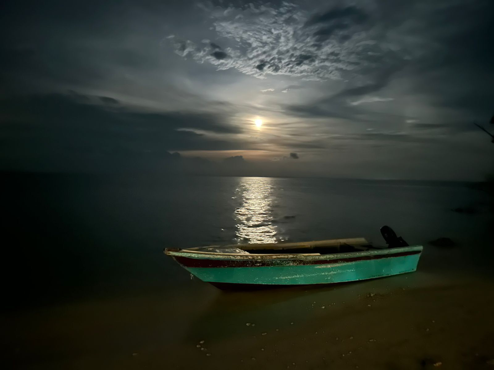 Um barco em águas calmas sob um céu iluminado pela lua.
