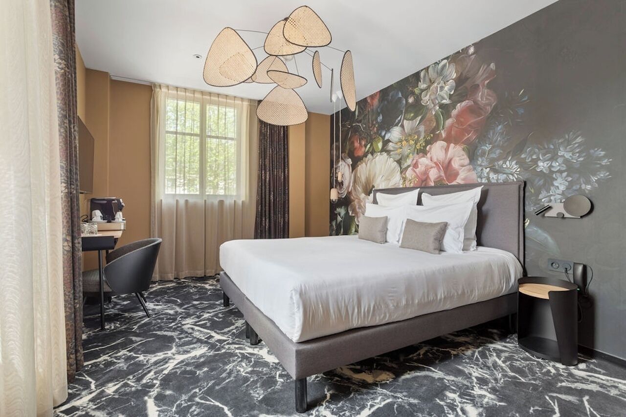A modern hotel room with a large bed, a desk, and a chair.