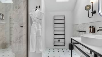A modern bathroom with a skylight, a white bathtub, a black towel rack, and a marble floor.