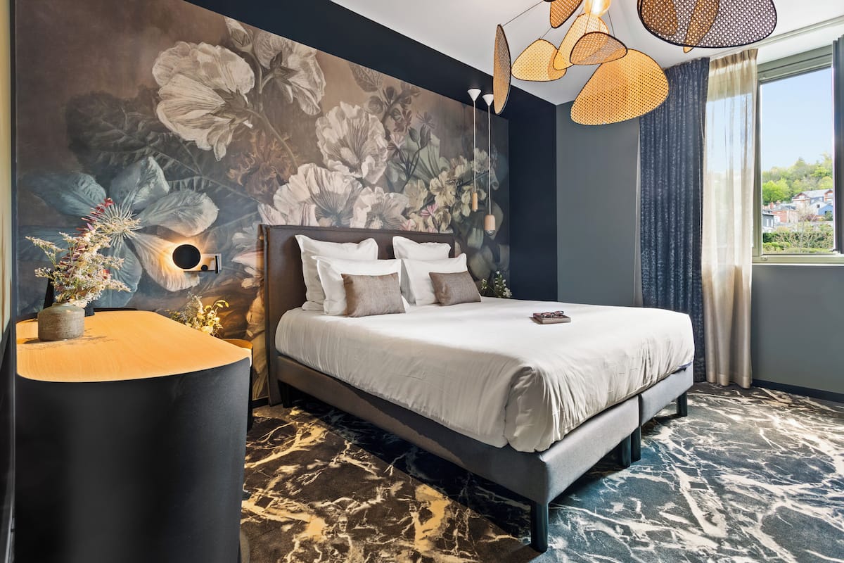 Un dormitorio moderno con una cama grande, una lámpara de pared y vistas al exterior.