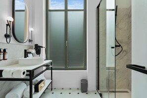 Un baño moderno con un espejo grande, un lavamanos, un inodoro y una ducha con mampara de vidrio.