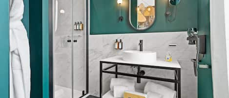 A modern bathroom with a glass-enclosed shower, a white sink with a mirror above it, and a towel rack with white towels.