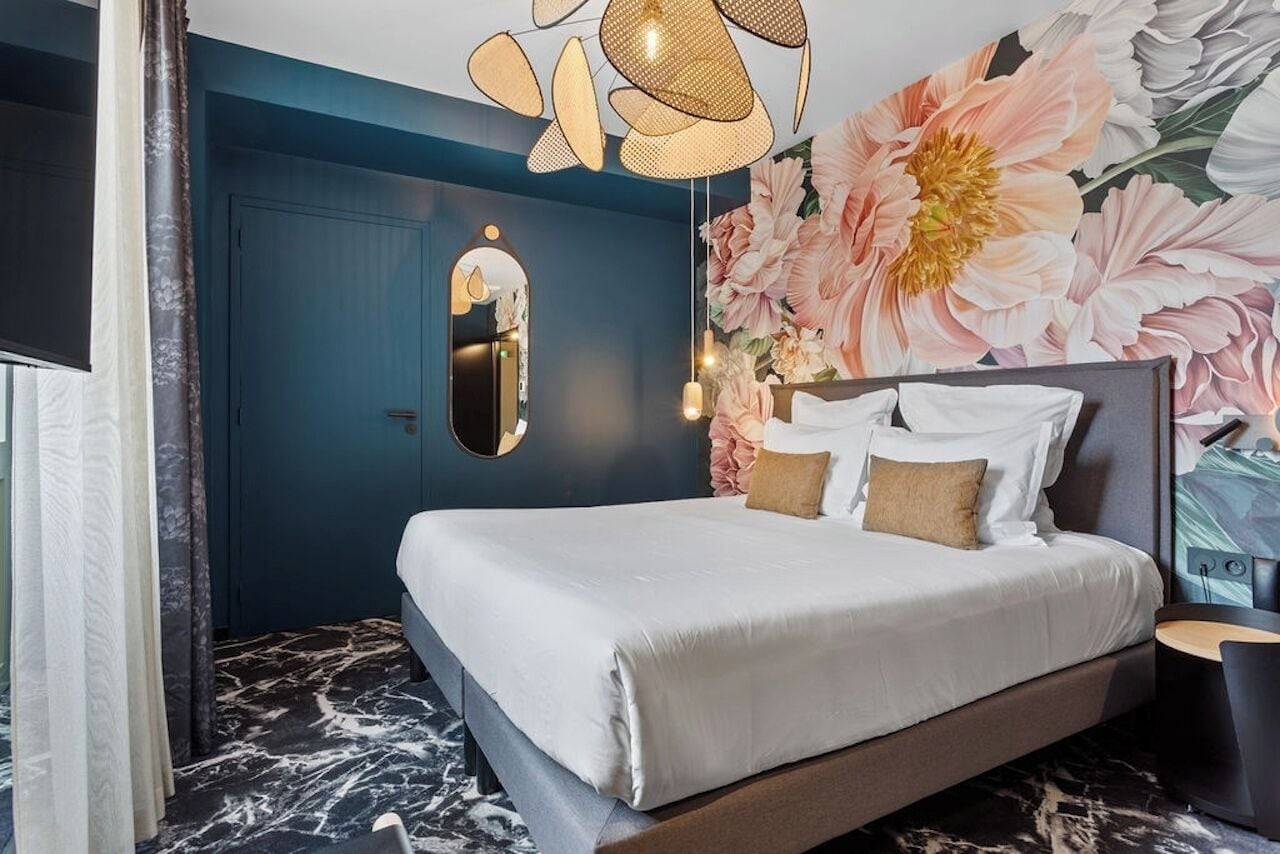Een moderne slaapkamer met een groot bed, een spiegel en bloemenbehang.