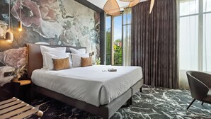 A modern hotel room with a large bed, a view of greenery through the window, and a marble-patterned floor. - Hôtel Le Rituel Honfleur (Honfleur)