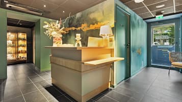 Een receptie met een balie, een wandlamp en een decoratieve vaas.