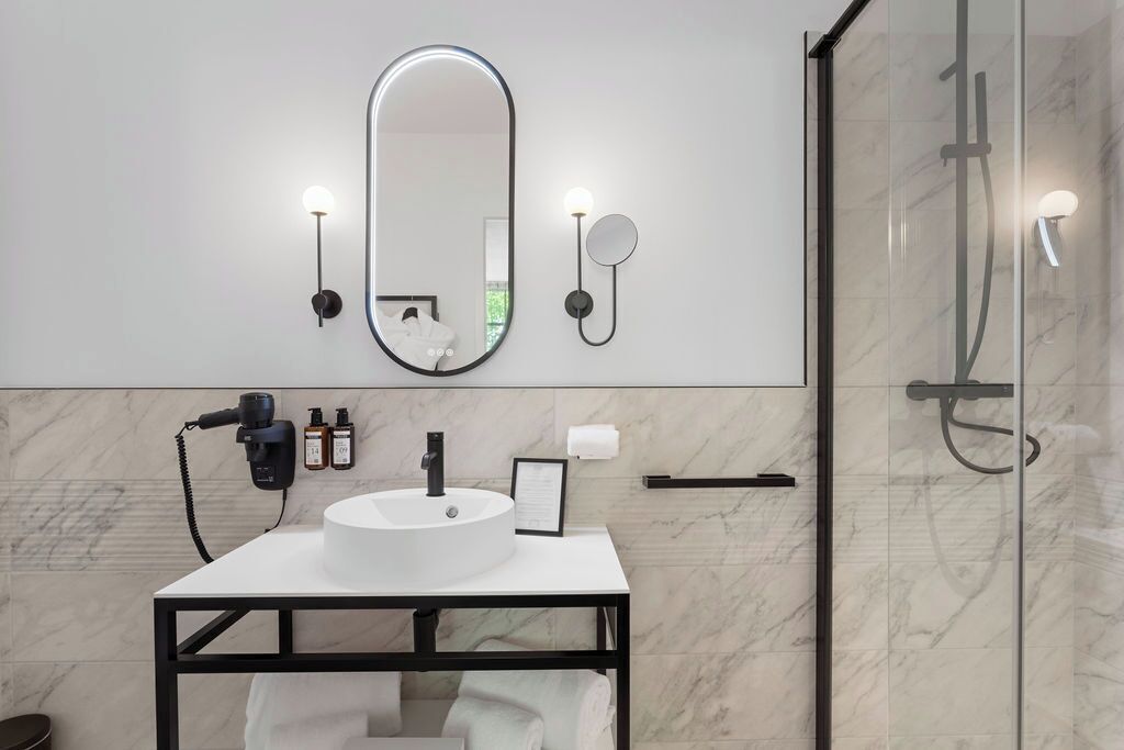 A modern bathroom with a white sink, a large mirror, and a glass shower enclosure.
