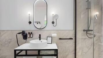 Une salle de bain moderne avec un lavabo blanc, un grand miroir et une cabine de douche en verre.