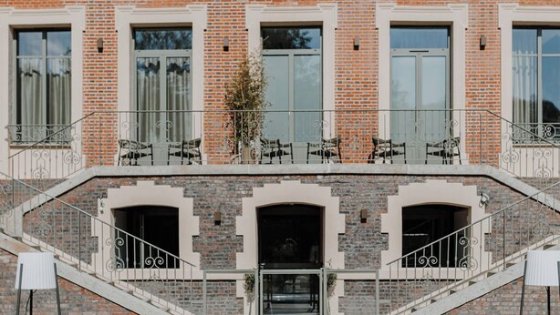 A pool area with a brick building in the background. - Hôtel Le Rituel Honfleur (Honfleur)