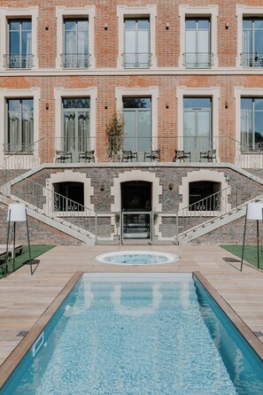 Un área de piscina con un edificio de ladrillo al fondo.