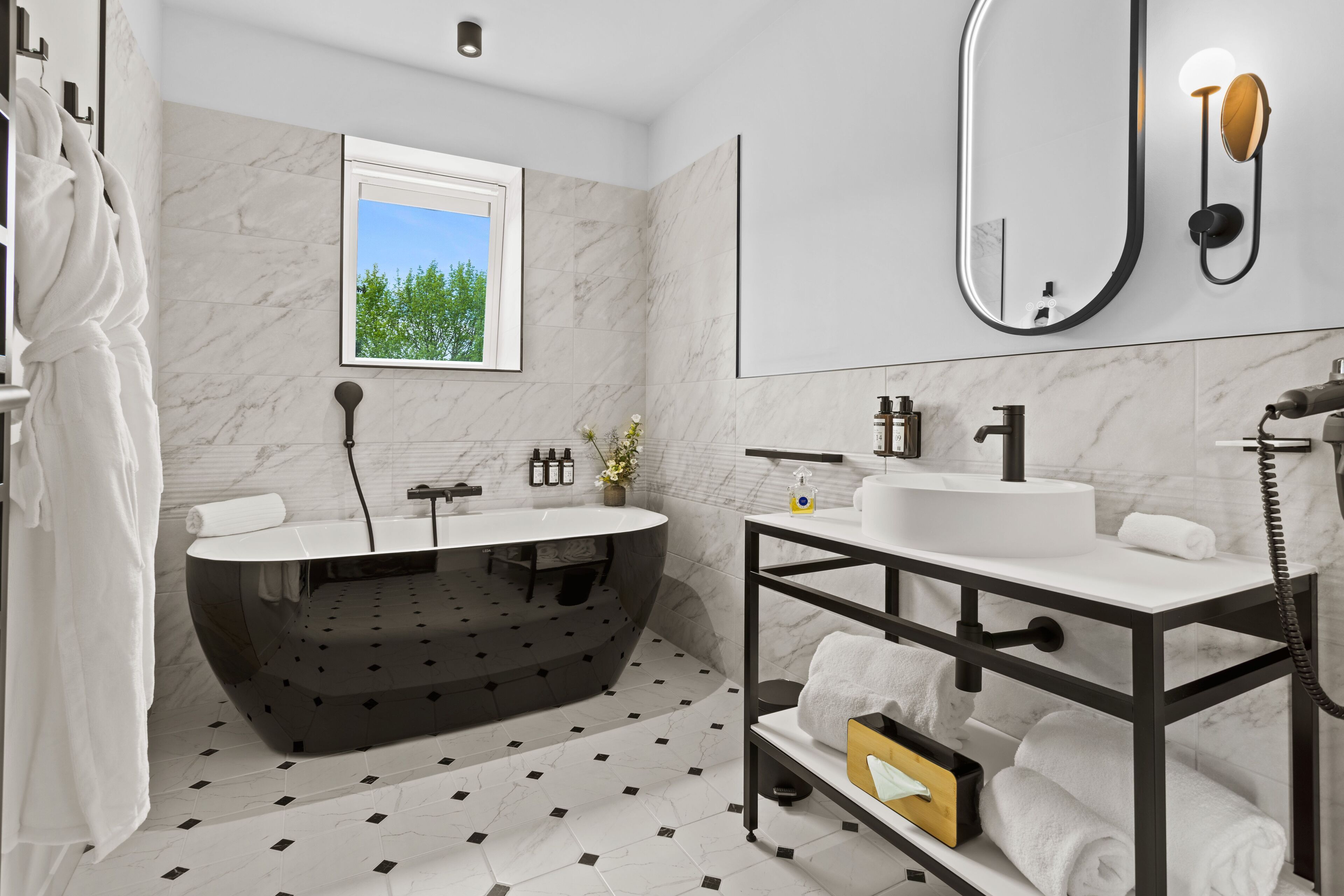 A modern bathroom with a freestanding bathtub, a large mirror, and a vanity with a sink and towel rack.