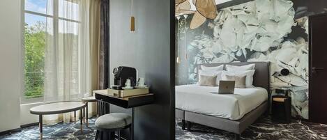 Una camera d'albergo moderna con un letto, una scrivania, una sedia e un'ampia finestra con tende.