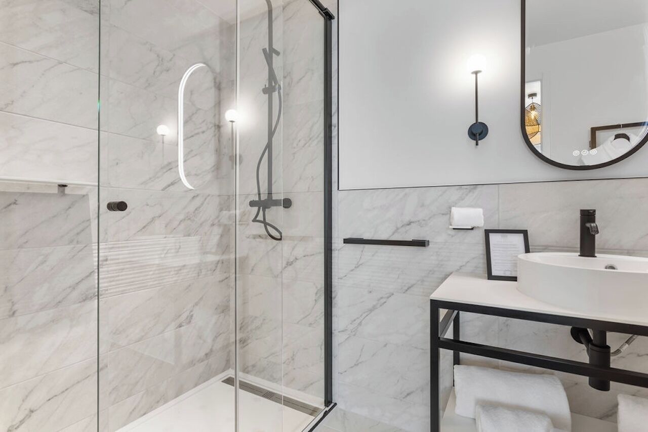 A modern bathroom with a glass-enclosed shower, a white sink, and a large mirror.