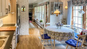 A kitchen with a wooden countertop, a stone wall, and a dining area with a round table and blue chairs.