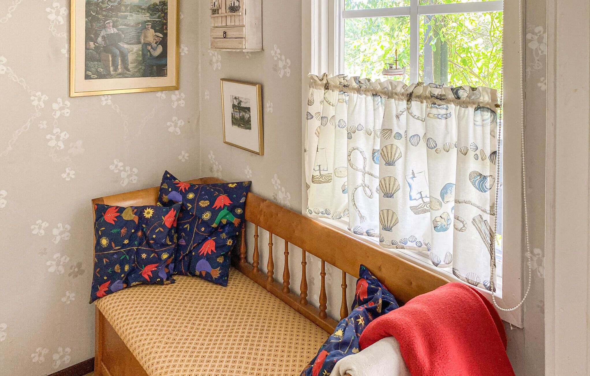 A cozy room with a wooden bed, patterned pillows, and a window with curtains.