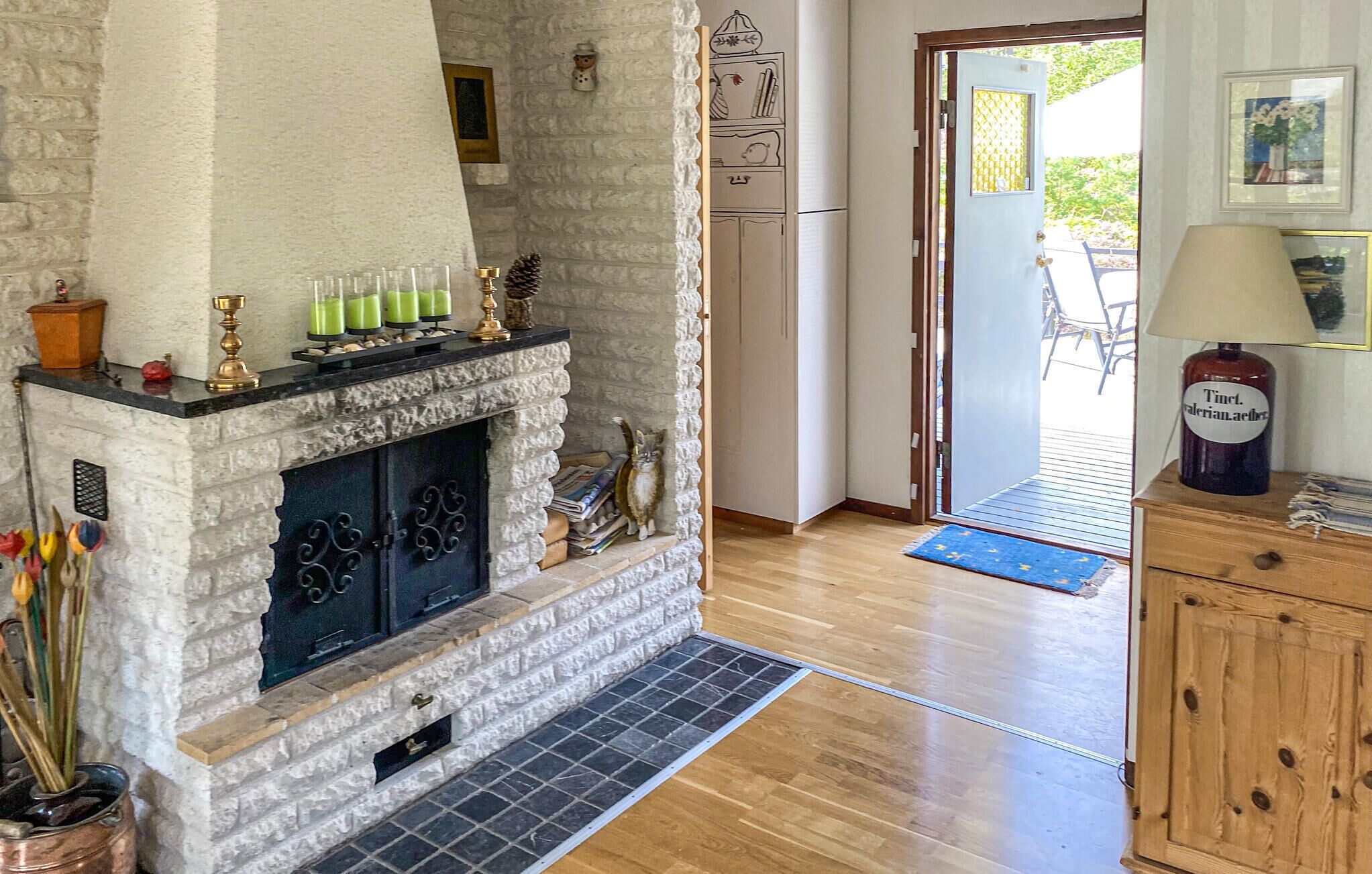 Una habitación acogedora con chimenea de piedra, un armario de madera y una puerta que da al exterior.