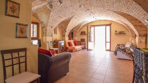 A spacious living area with a high arched brick ceiling, a sofa, a chair, and a small table.