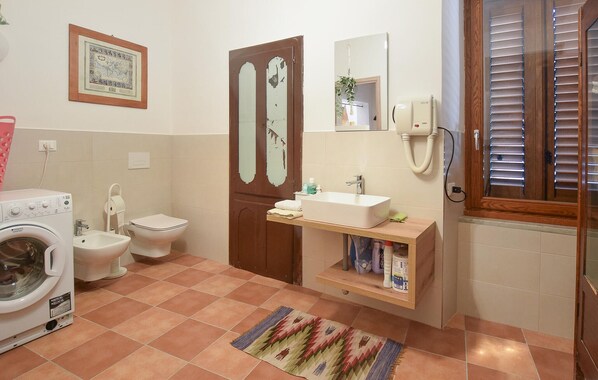 A bathroom with a washing machine, toilet, sink, and a mirror.