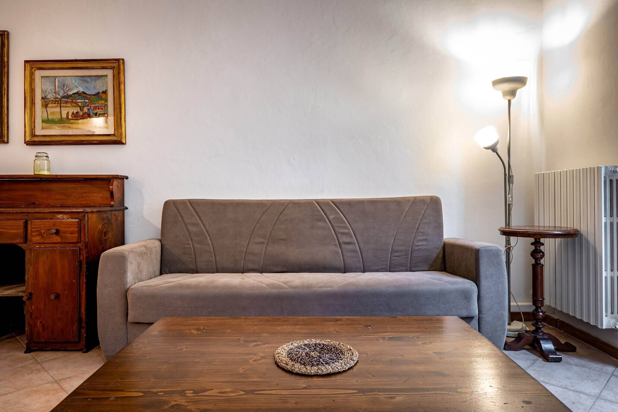 Un salon avec un canapé, une table basse en bois, une lampe et un radiateur.