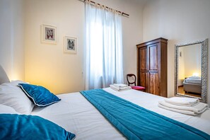 Une chambre d’hôtel avec un lit, une armoire, un miroir et deux tableaux encadrés au mur.
