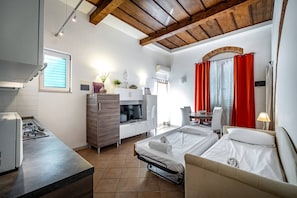 Una camera d'albergo compatta con angolo cottura, un letto, una scrivania e una sedia.