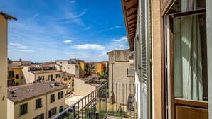 A balcony with a metal railing overlooking a residential area with multiple buildings.