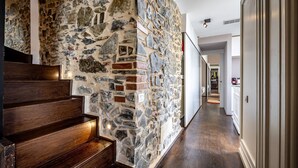 A hallway with a stone wall, wooden steps, and a wooden floor.