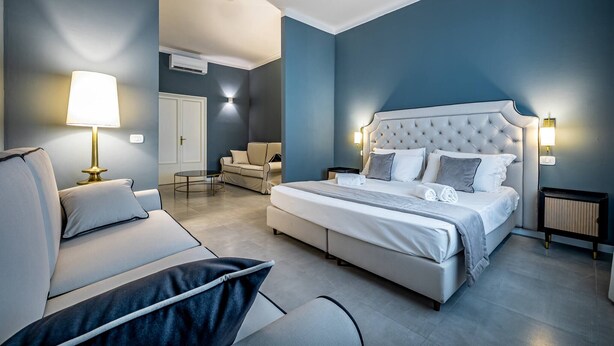 Een moderne slaapkamer met een groot bed, een bank, een stoel en een nachtkastje.