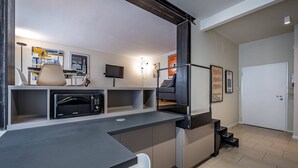 A modern kitchen with a built-in microwave, a dining area with a chair, and a staircase leading to an upper level.