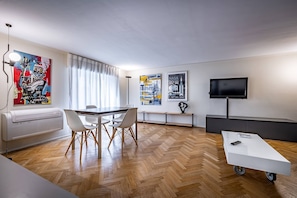 Un soggiorno moderno con zona pranzo, televisione a schermo piatto e opere d'arte alle pareti.
