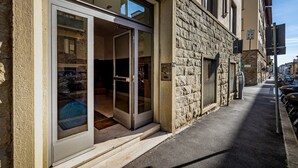 A building with a stone facade, a glass entrance, and a parking meter on the sidewalk.